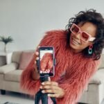 Créatrice de contenu à Kinshasa filmant une vidéo avec un smartphone. Talent pour campagne de marketing d'influence Celebrity Agency.