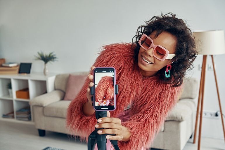 Créatrice de contenu à Kinshasa filmant une vidéo avec un smartphone. Talent pour campagne de marketing d'influence Celebrity Agency.